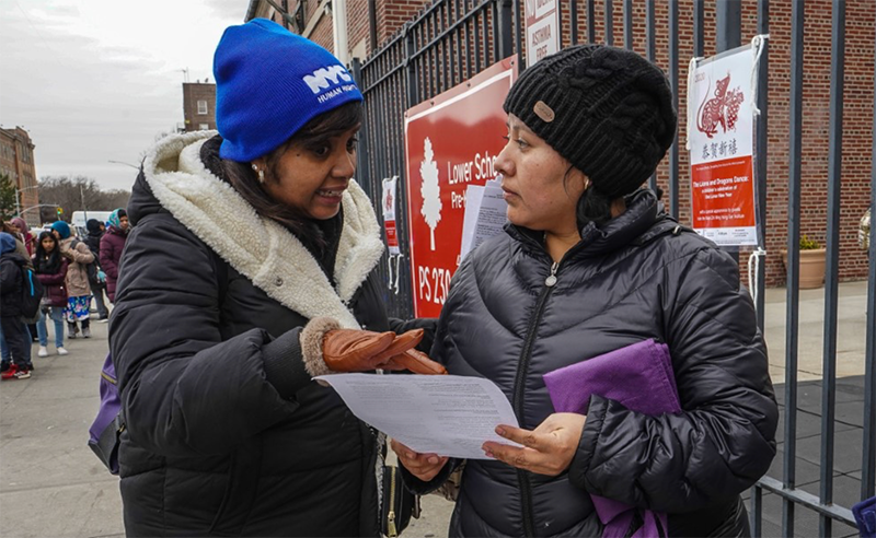 Commission staffer talking with New Yorker on the street, pointing at Commission literature.