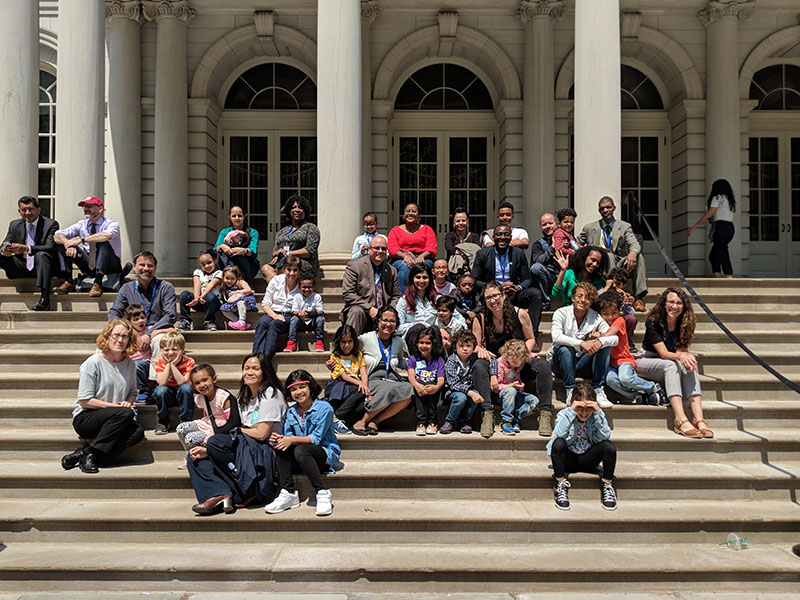 Staff and family sitting at City Hall steps