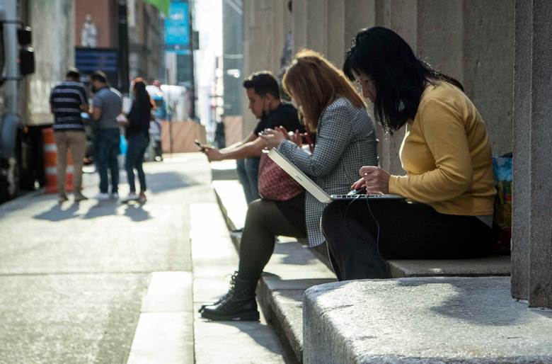 A woman sitting on a bench looking at her phone.  Description generated by AI