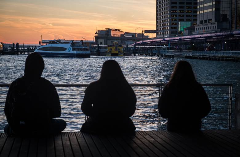 Three people sitting on a pier.  Description generated by AI