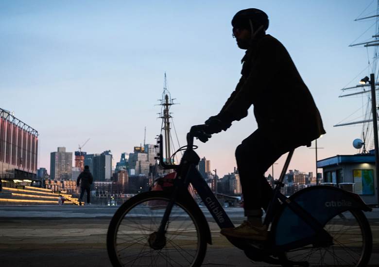 A man riding a bike in a city.  Description generated by AI