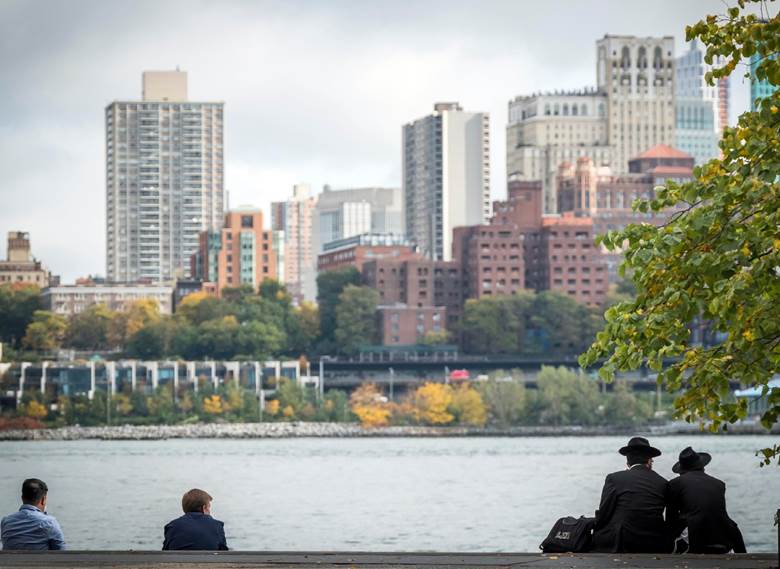Three people sitting on a bench by a river.  Description generated by AI