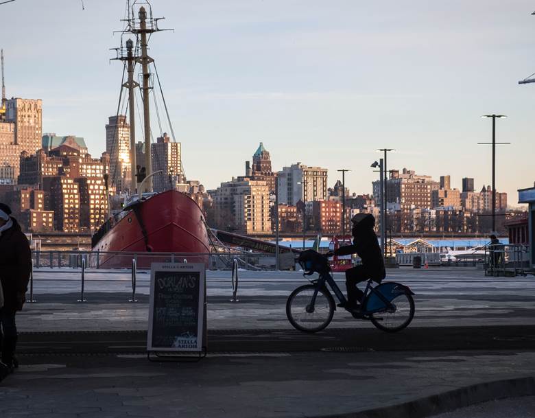 A man riding a bike in front of a large boat.  Description generated by AI