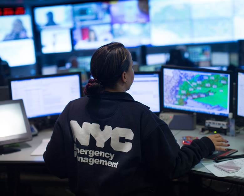A woman in a NYC Emergency Management uniform is working at a computer.  Description generated by AI