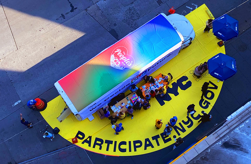 An aerial shot of the people's bus wiht people gather around it