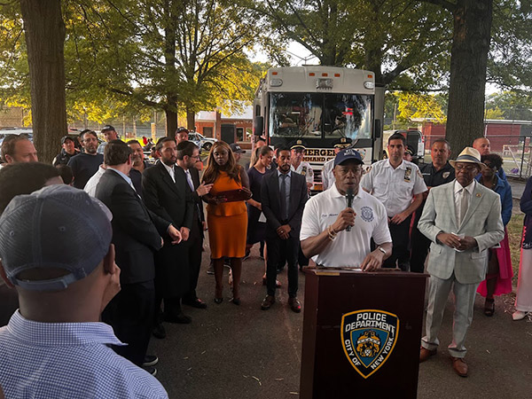 mayor adam stand at the podium speaking at a park