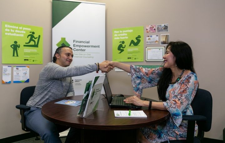 Female financial empowerment counselor shakes hands with a male client across a table
                                           