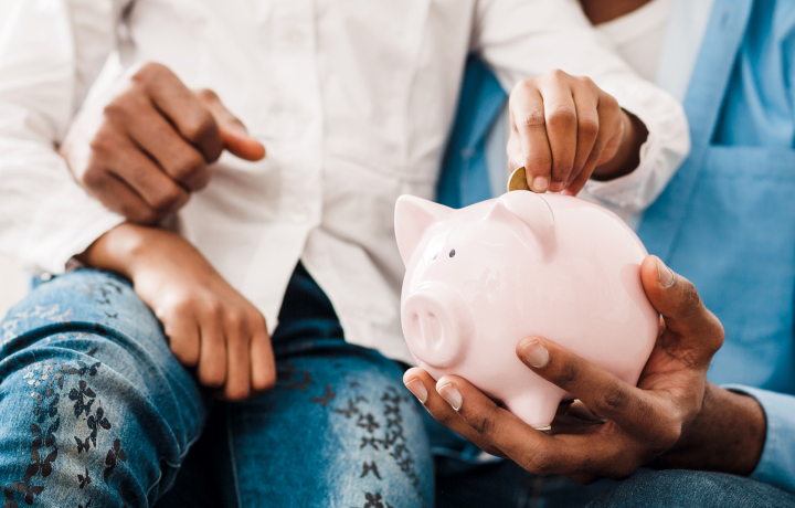Father and daughter put money in a piggy bank
                                           