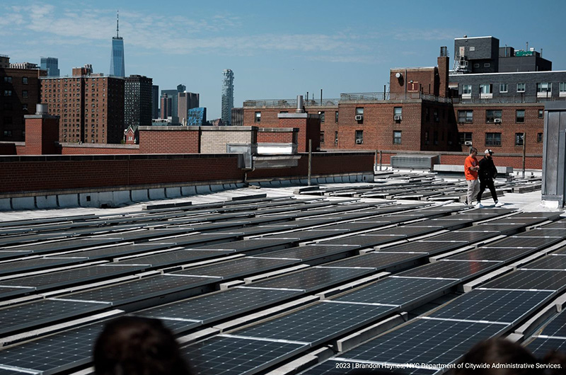 Dedicated Agency Energy Staff Solar panels on roof top of building with lower Manhattan view in the background