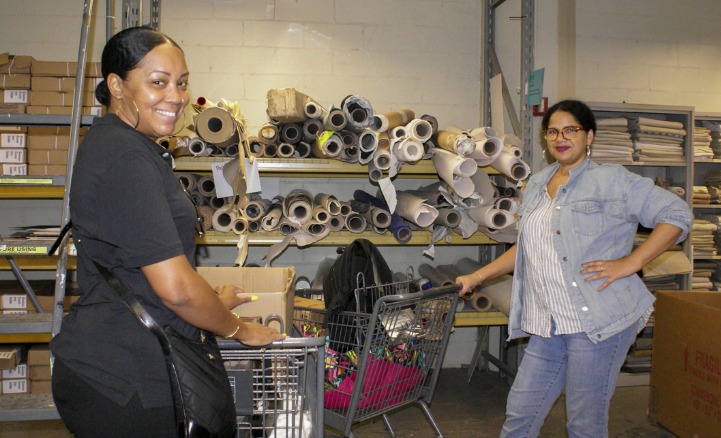 Two teachers smile with shopping carts in the MFTA warehouse.
                                           