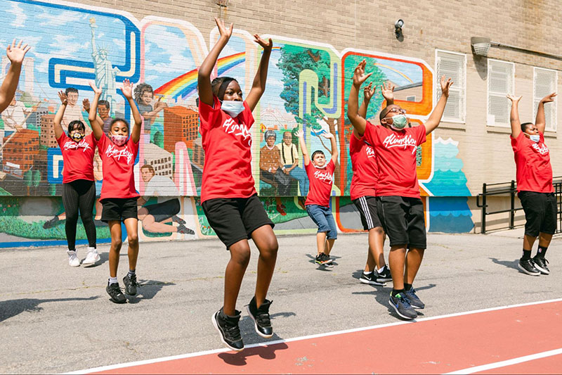 People gather in front of a colorful mural celebrating Bed-Stuy and its icons