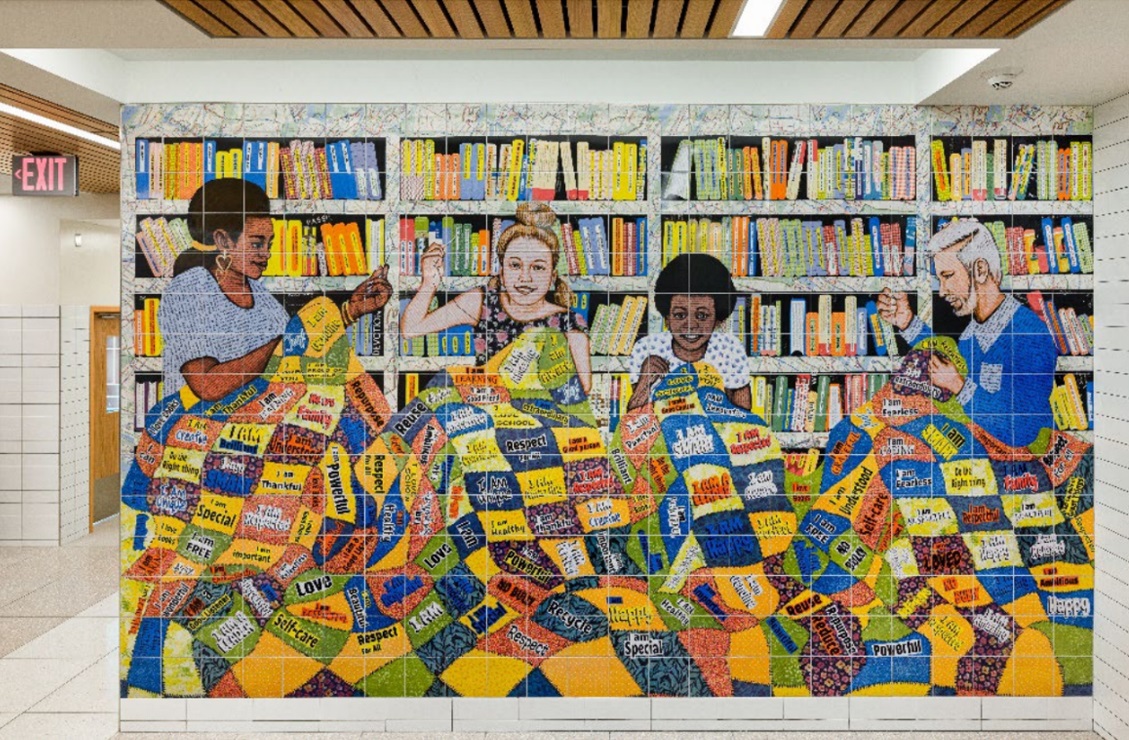 A brightly colored ceramic installation of people sewing a quilt in a library setting. 