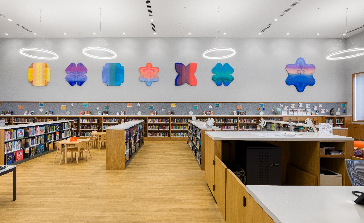 Emily Kiacz's colorful shape installation is mounted above bookshelves.