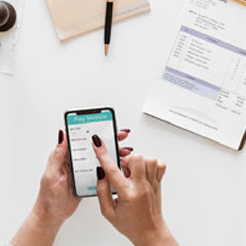 A hand with a cell phone and a paper