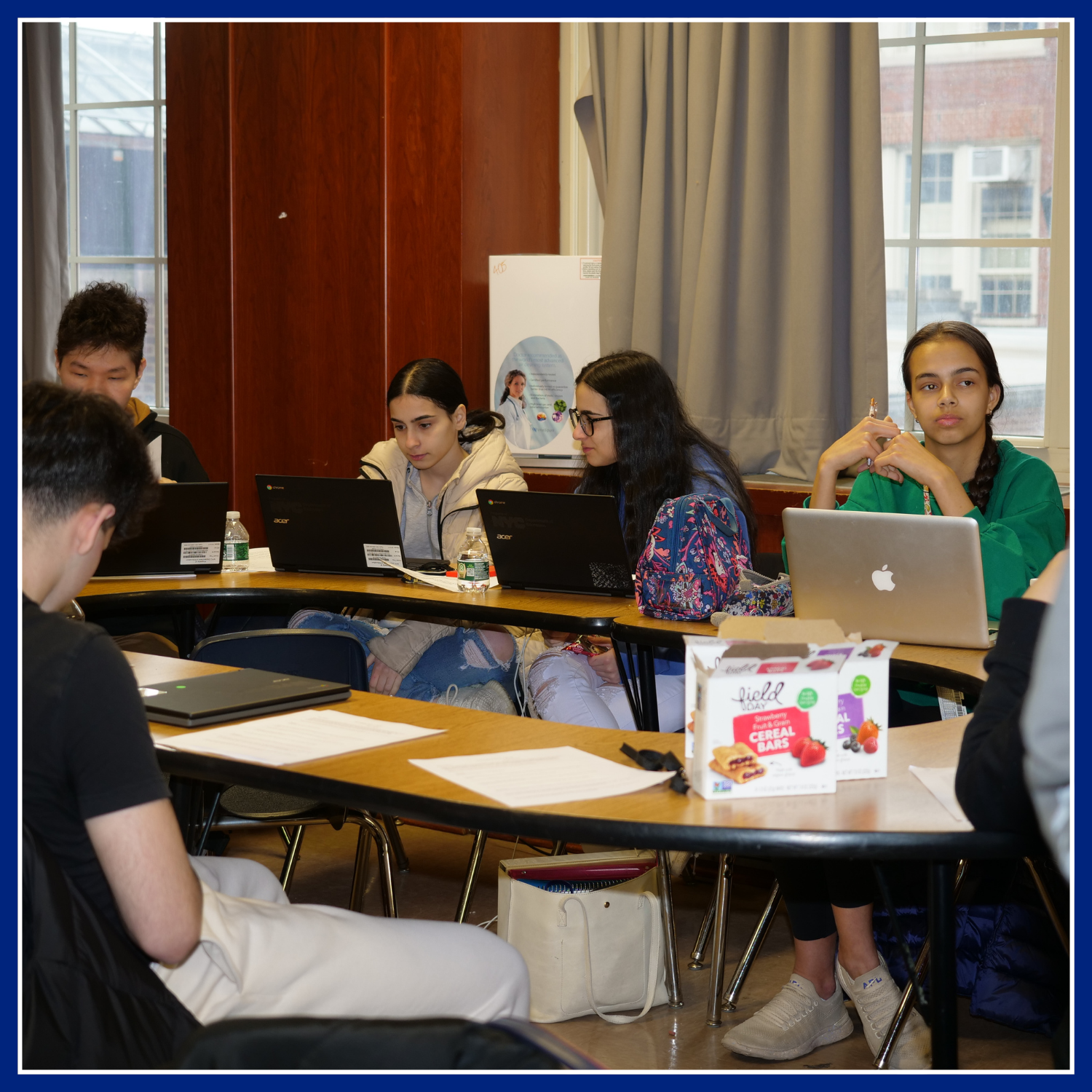 circle of participants sitting in table in front of their laptops in a classroom.  The Comprehensive After School System of NYC (COMPASS NYC) programs.