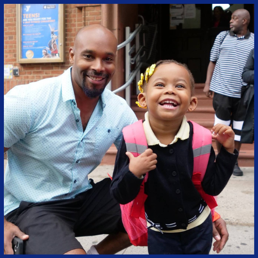Father and young daughter pose for picture in front of school