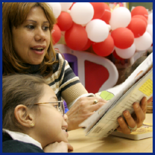 woman reading a book to female child in classroom