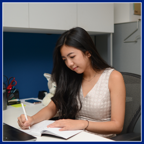 Girl posing writing while sitting at a work desk. The Advance & Earn Program.