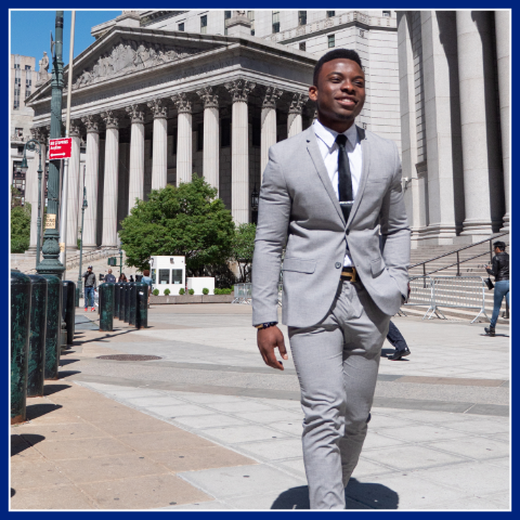 Young men wearing a suit and tie enjoys a walks outside in front a court building. NYC Ladders for Leaders Program.