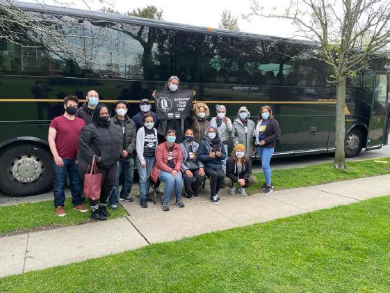 This image shows a group of tenant organizers standing in front of a bus holding up a sign.