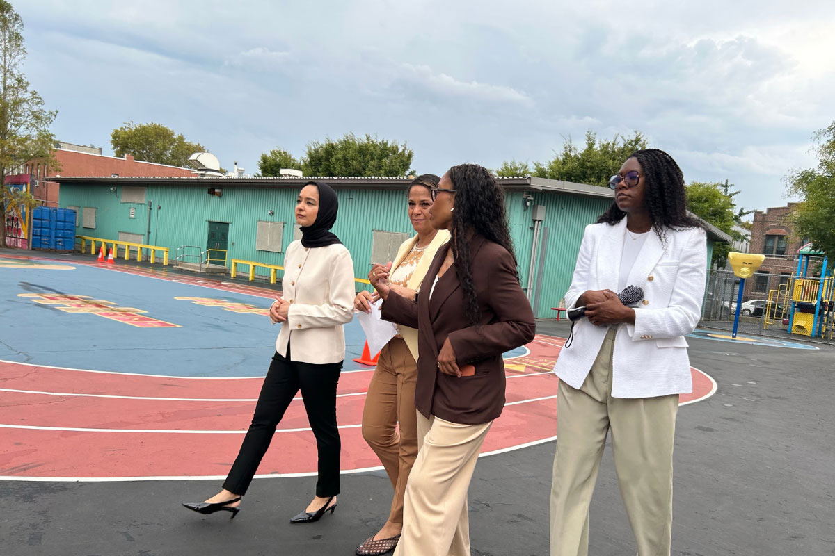 A photo of a group of people visiting a school and walking outside on a sports track.