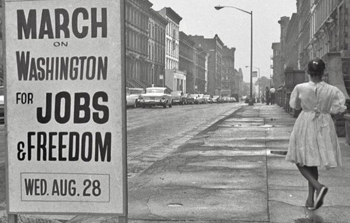 Black and white photo of girl standing next to sign that says March on Washington for Jobs & Freedom