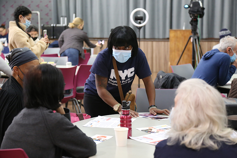 A P E U Specialist leans over a table and talks to older adults