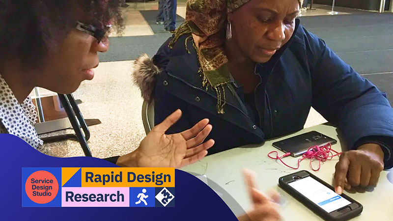 Two women sit at a table, discussing a mobile application. One woman gestures while speaking, and the other interacts with the phone screen. A Service Design Studio Rapid Design Research logo banner overlays the image.