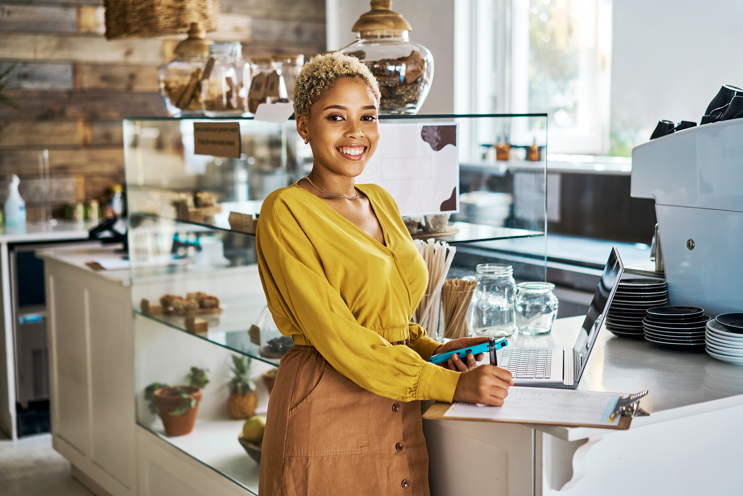 Woman standing in her small business cafe smiling at the camera
                                           