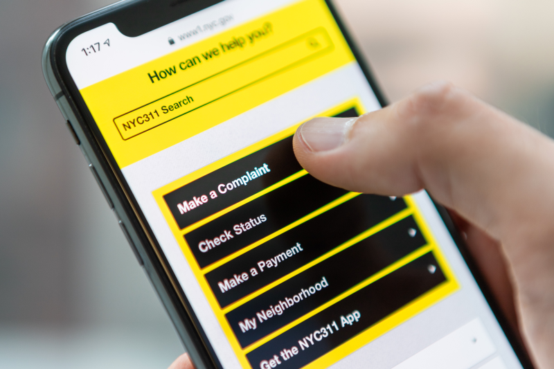 Close-up of a Cellphone showing a thumb placed on make a complaint option on the screen Image of a cellphone being used to make a complaint