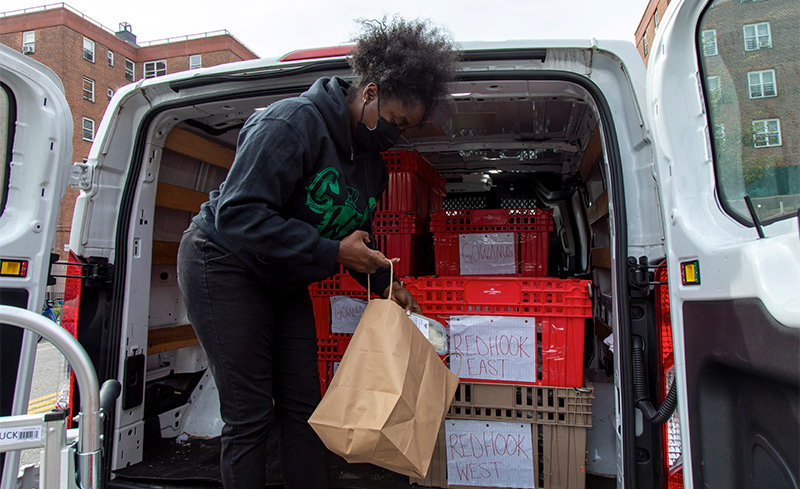 Woman loading groceries into paper bag in the back of a truck