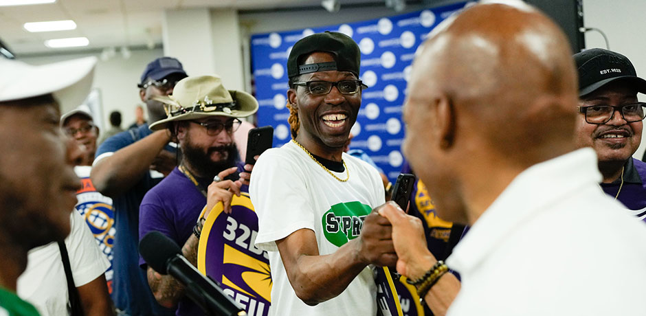 A male union worker from 32BJ SEIU shakes hands with Mayor Eric Adams in a crowd
                                           