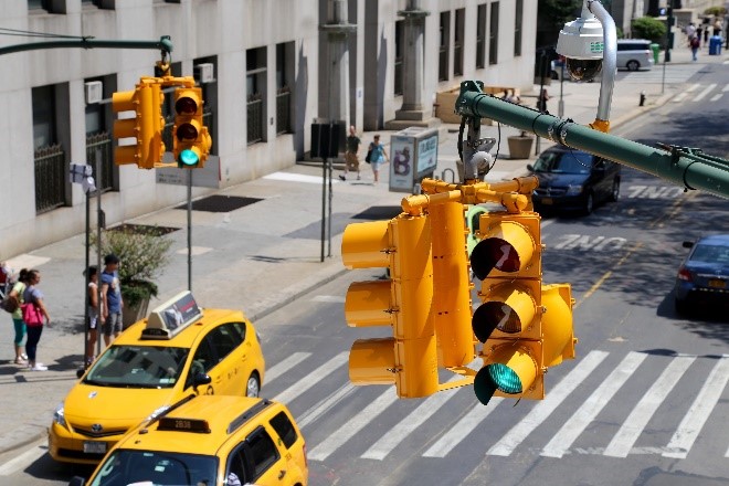 Traffic signals glow green while yellow taxis travel along a busy New York City street.