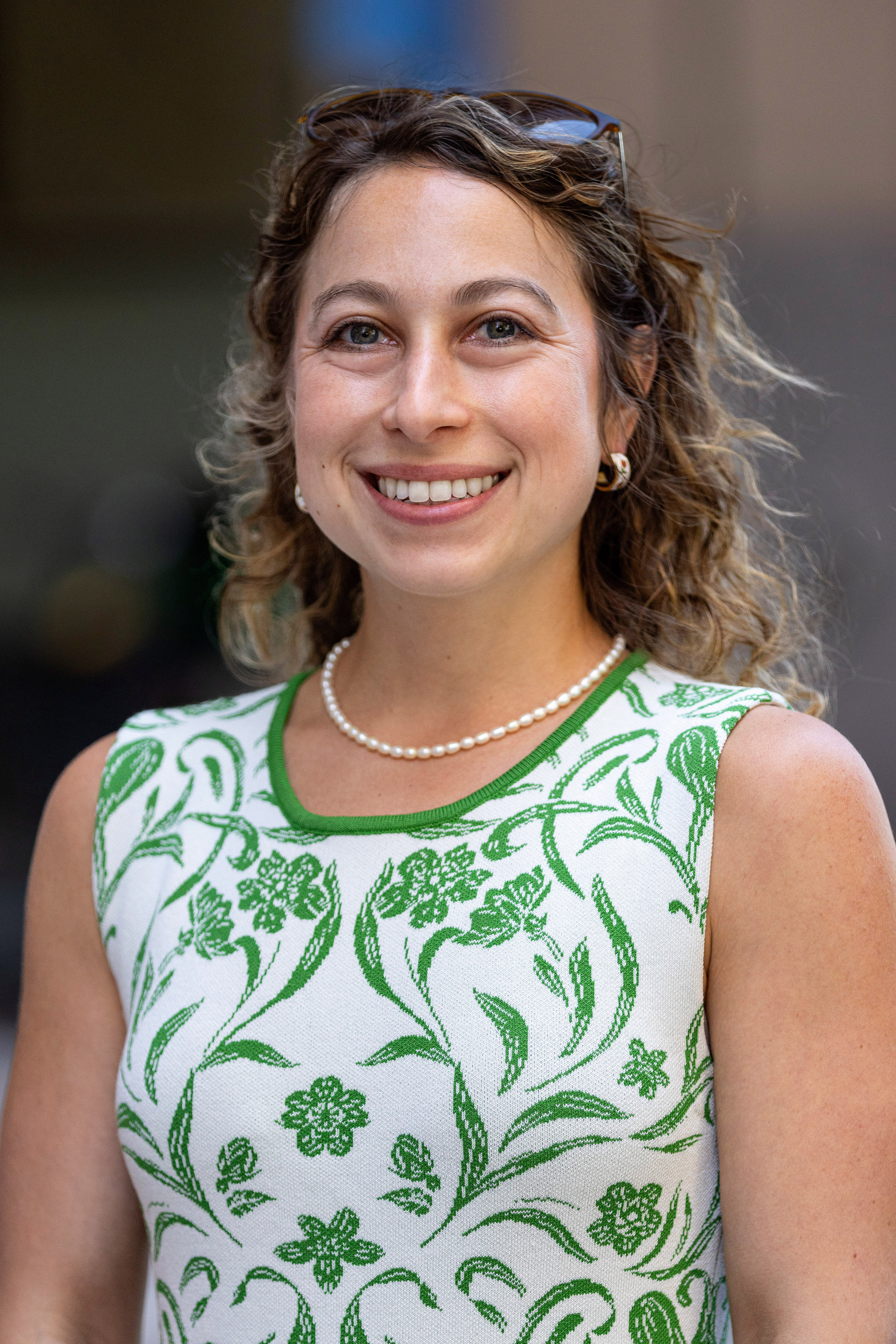 Portrait of New York City Department of Transportation's Manhattan Borough Commissioner Danielle Zuckerman. She has curly brown hair and is wearing a green and white sleeveless top.