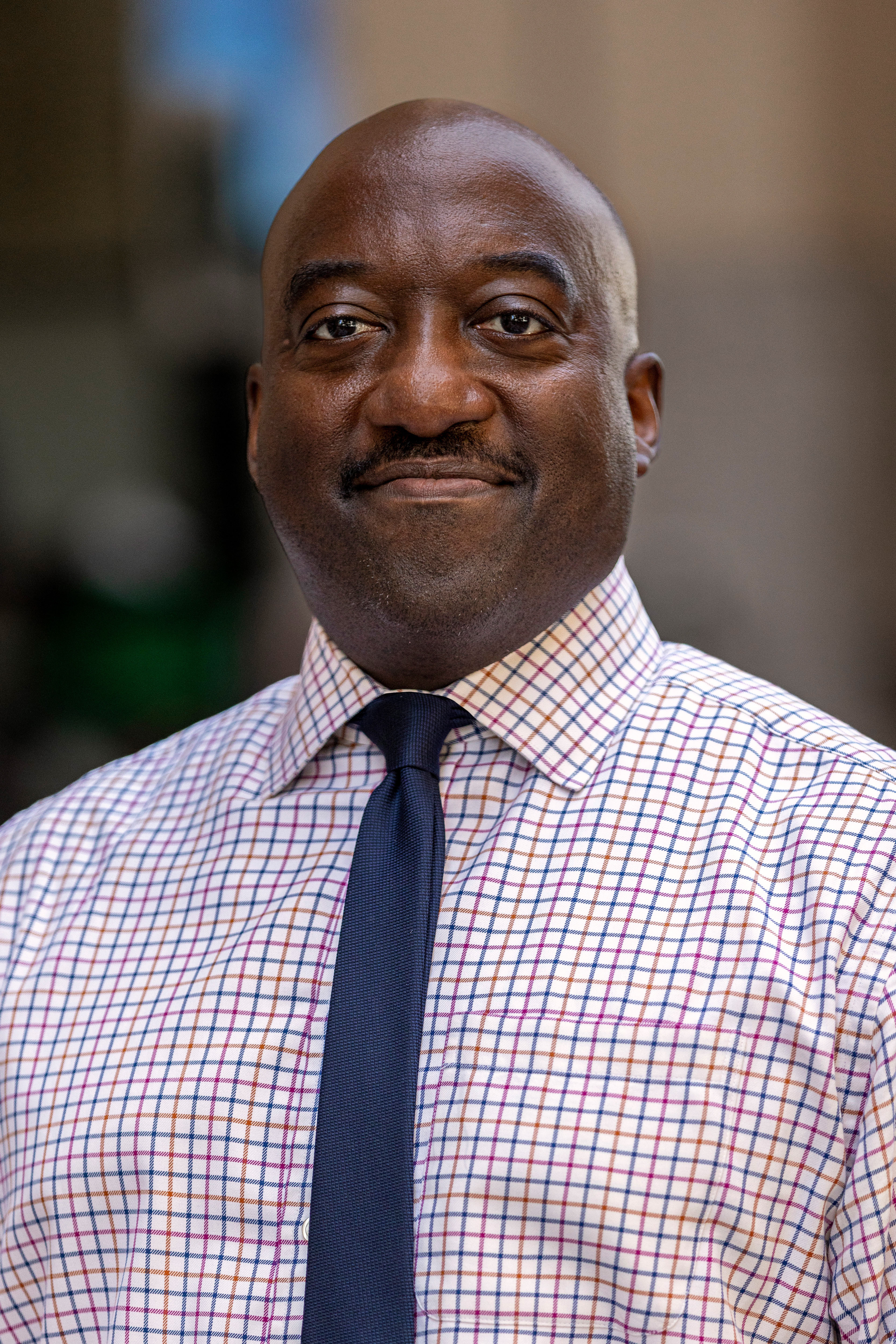 Portrait of New York City Department of Transportation's Brooklyn Borough Commissioner Keith Bray. He is wearing a collared shirt with a red and blue checkered pattern and a navy blue tie.