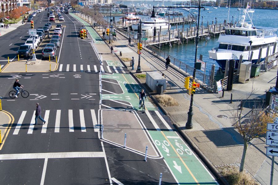A wide road featuring a greenway with green bike lanes.