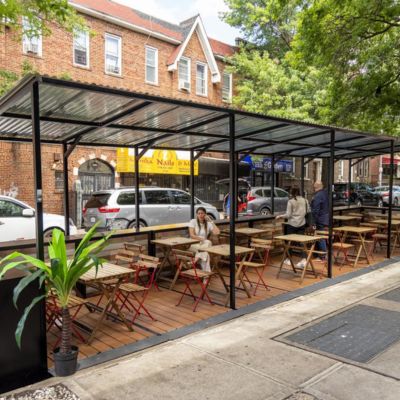 An outdoor dining structure featuring tables, chairs, and other movable elements.