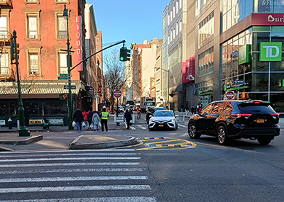 A car turns left around a median extension treatment consisting of box markings and rubber speed bumps.