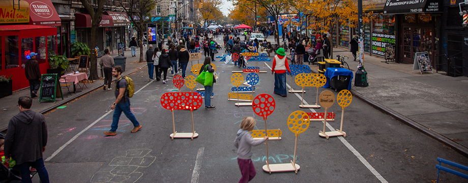 A street in New York City is closed to traffic and open for people to walk and play on.