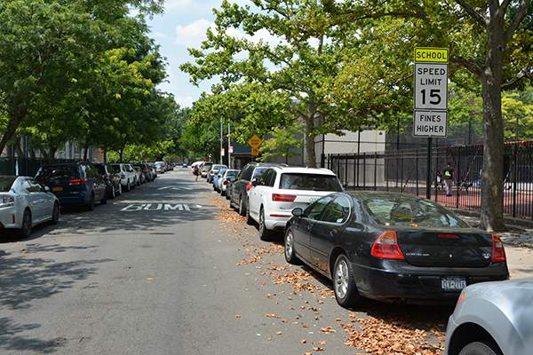 15 mph School Slow Zone sign on street in front of a playground